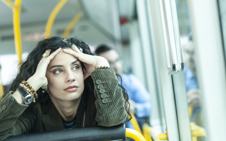 Pensive woman traveling with public transport, hands on head.