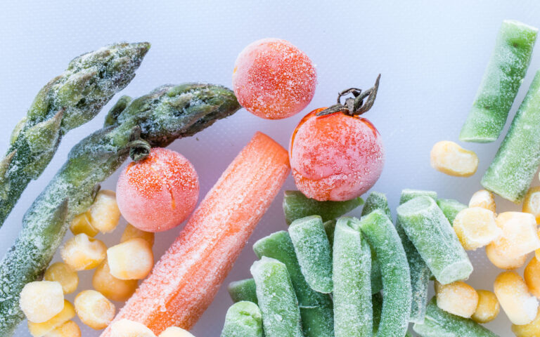 frozen vegetables: cherry tomatoes. asparagus, corn, baby carrot, french beans, peas  on white cutting board, top view, macro frozen vegetables: cherry tomatoes. asparagus, corn, baby carrot, french beans, peas  on white cutting board, top view, macro