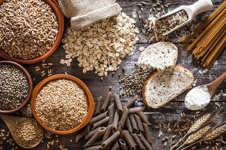 Top view of wholegrain and cereal composition shot on rustic wooden table. This type of food is rich of fiber and is ideal for dieting. The composition includes wholegrain sliced bread, various kinds of wholegrain pasta, wholegrain crackers, grissini, oat flakes, brown rice, spelt and flax seeds. Predominant color is brown. DSRL studio photo taken with Canon EOS 5D Mk II and Canon EF 100mm f/2.8L Macro IS USM