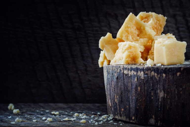 pieces of parmesan cheese on dark background with copy space