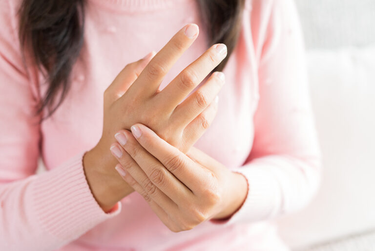Closeup woman sitting on sofa holds her wrist hand injury, feeling pain. Health care and medical concept. Closeup woman sitting on sofa holds her wrist hand injury, feeling pain. Health care and medical concept.