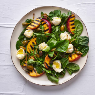Insalata con pesche grigliate, bocconcini di mozzarella e frutti di cappero