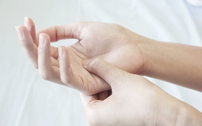 closeup of a woman pressing the middle of her palm with her thumb to relieve pain due to a tendinitis caused by an excessive use of computer, laptop, phone. closeup of a woman pressing the middle of her palm with her thumb to relieve pain due to a tendinitis caused by an excessive use of computer, laptop, phone.