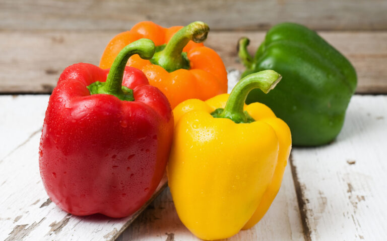 Whole red, yellow, orange and green bell peppers on old painted and peeling wood boards. Whole red, yellow, orange and green bell peppers on old painted and peeling wood boards.