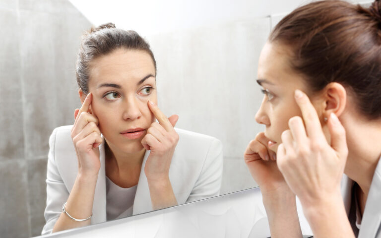 Reflection in the mirror. Woman looks in the mirror noticing the first wrinkles Reflection in the mirror. Woman looks in the mirror noticing the first wrinkles