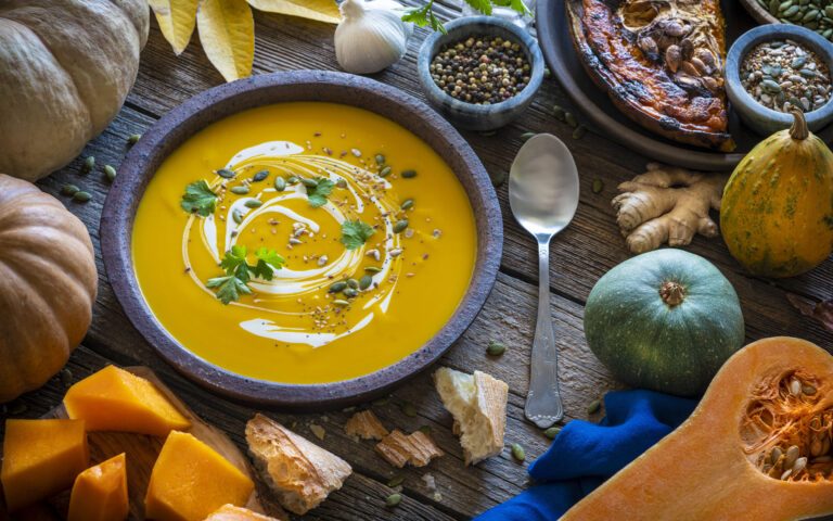 Autumn pumpkin soup and ingredients on rustic wooden table