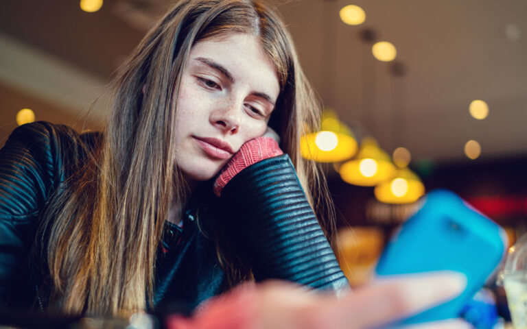 Teenage girl in cafe text messaging on smartphone Teenage girl in cafe text messaging on smartphone