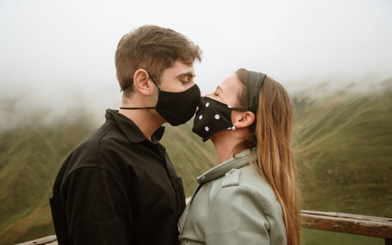 Young couple wearing face masks and kissing during the COVID-19 Coronavirus pandemic