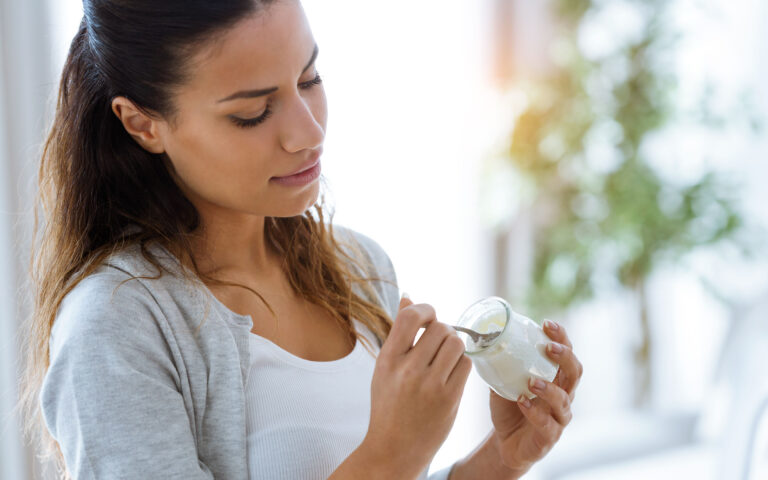 Shot of pretty young woman eating yogurt at home. Shot of pretty young woman eating yogurt at home.