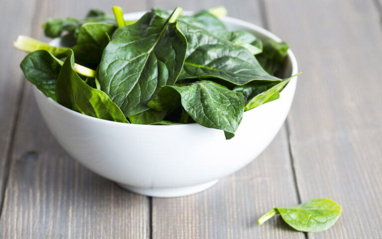 Fresh spring baby leaves of spinach on wood table.