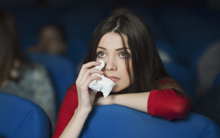 Beautiful, sad woman watching the movie at the cinema and crying Beautiful, sad woman watching the movie at the cinema and crying