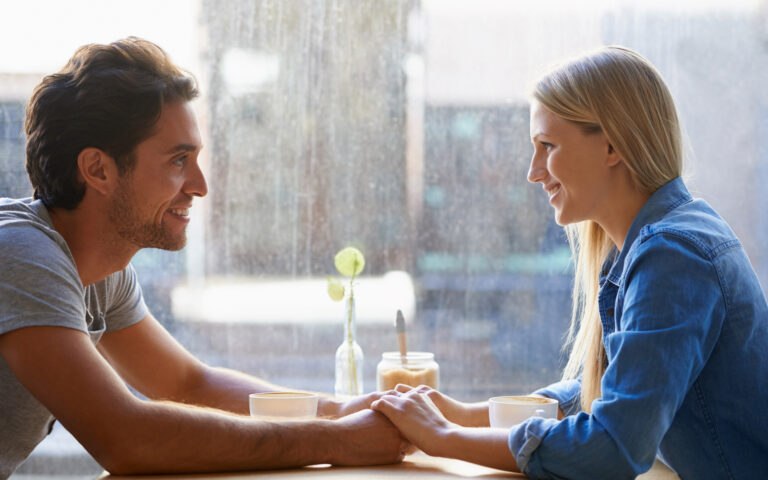 A young couple sitting hand-in-hand in a coffee shop A young couple sitting hand-in-hand in a coffee shop