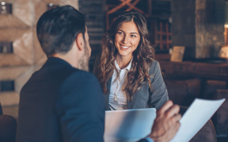 Two people in formal businesswear talking and smiling