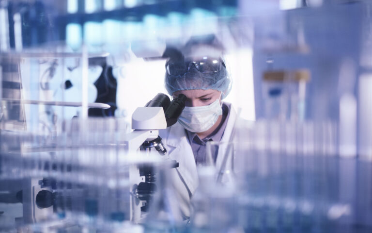 Female microbiologist studying coronavirus with microscope. Fighting with pandemic