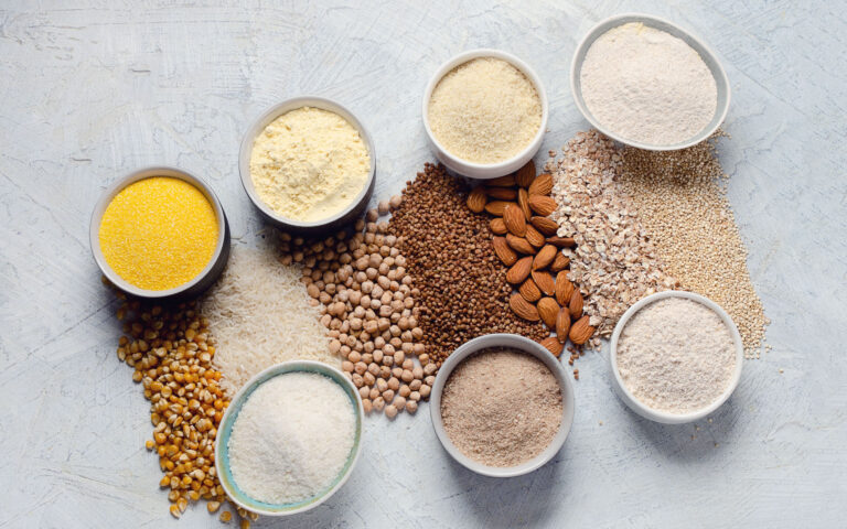 Various gluten free flour - chickpeas, rice, buckwheat, quinoa, almond, corn, oatmeal on grey background.