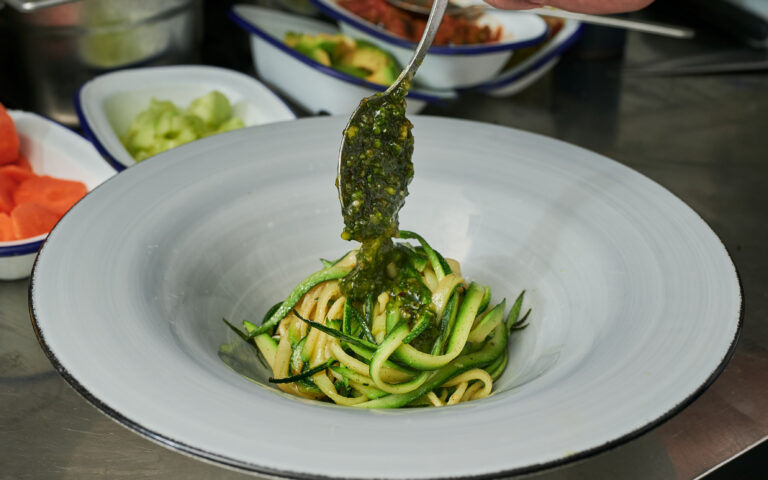 detail view of Chef inside the kitchen preparing zucchini spaghetti with pistachio pesto dish detail view of Chef inside the kitchen preparing zucchini spaghetti with pistachio pesto dish