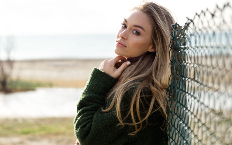Portrait of beautiful young woman posing in a cold winter on the beach.