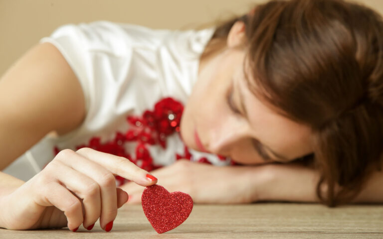 Sad lonely woman holding red heart.  Being alone on Valentine's day. Heartbreak, divorce or breakup concept.