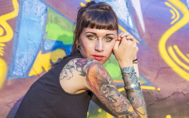 tattooed rebel girl posing against a wall painted with colorful graffiti tattooed rebel girl posing against a wall painted with colorful graffiti