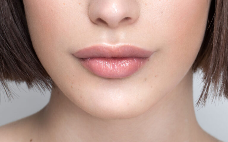 Close up studio shot of a beautiful girl with short brown hair, freckles and soft make up.