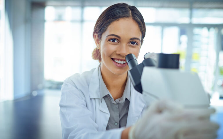 Portrait of a young scientist using a microscope in a lab Portrait of a young scientist using a microscope in a lab
