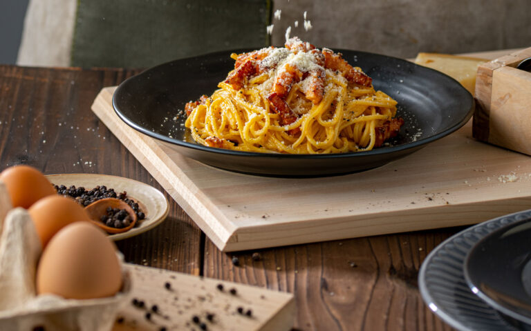 Delicious pasta carbonara on black plate.