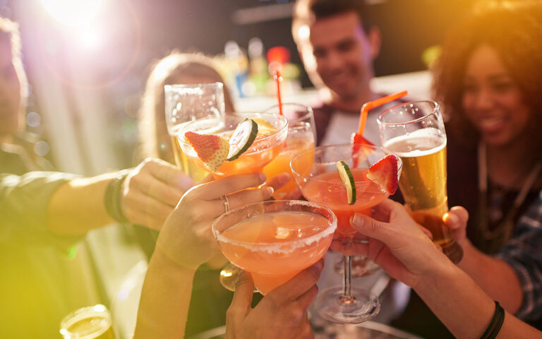 Shot of a group of people toasting with their drinks at a nightclub Shot of a group of people toasting with their drinks at a nightclub