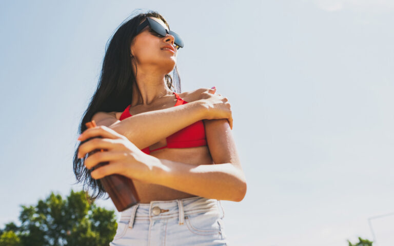 Young smiling joyful caucasian woman, girl in sunglasses having rest, sunbathing on the beach in bright summer day. Concept of summer rest, vacations, lifestyle