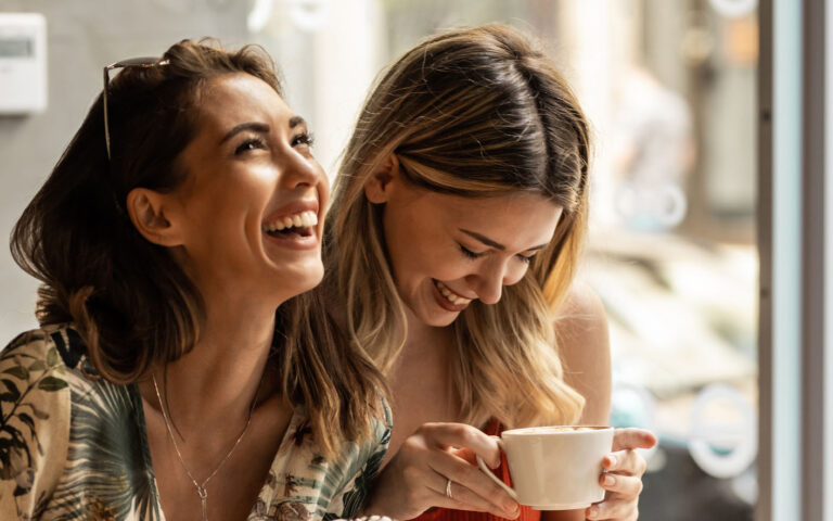 Beautiful happy women talking and laughing while drinking coffee together in coffee shop. Beautiful happy women talking and laughing while drinking coffee together in coffee shop.
