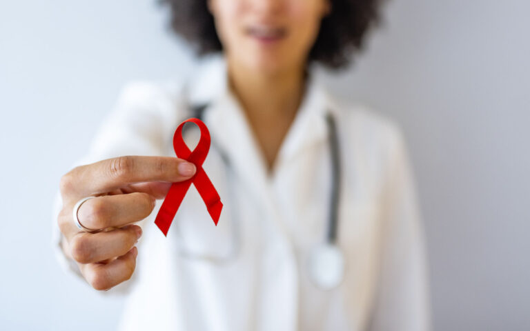 AID, HIV red ribbon. Symbol of awareness, charity, support in disease, illness. Medical health care, help and hope. Sign of healthcare medicine campaign holding in female doctor. AID, HIV red ribbon. Symbol of awareness, charity, support in disease, illness. Medical health care, help and hope. Sign of healthcare medicine campaign holding in female doctor.