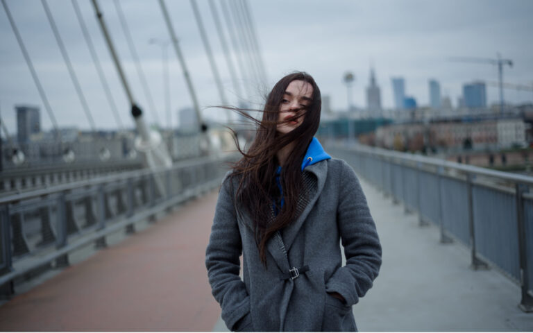 View on the bridge with young woman walking back during the windy weather in Warsaw city, Poland