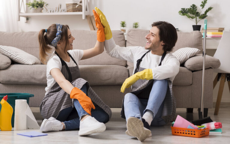 Housekeeping And Cleaning Service Concept. Happy Couple Giving High Five To Each Other After Spring-Clean In Apartment Housekeeping And Cleaning Service Concept. Happy Couple Giving High Five To Each Other After Spring-Clean In Apartment