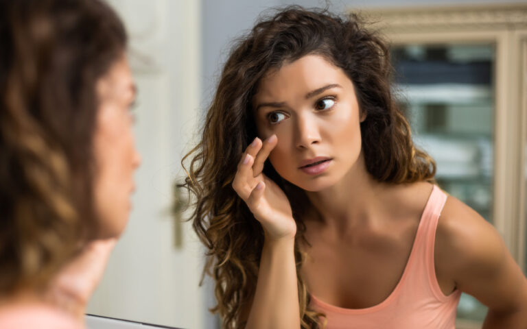 Tired woman looking her eye bags in the bathroom. Tired woman looking her eye bags in the bathroom.