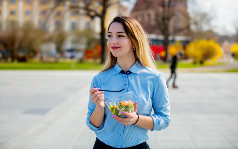 Young business woman with salad lunch box on outdoor in sunny day.