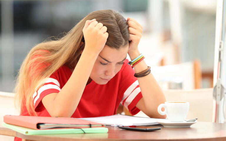 Single frustrated student girl trying to understand notes sitting in a bar Single frustrated student girl trying to understand notes sitting in a bar
