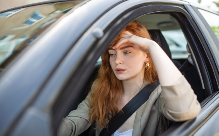 Nervous female driver sits at wheel, has worried expression as afraids to drive car by herself for first time. Frightened woman has car accident on road. People, driving, problems with transport