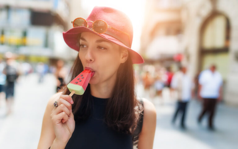 Young woman eating ice cream in the summer on the street Young woman eating ice cream in the summer on the street
