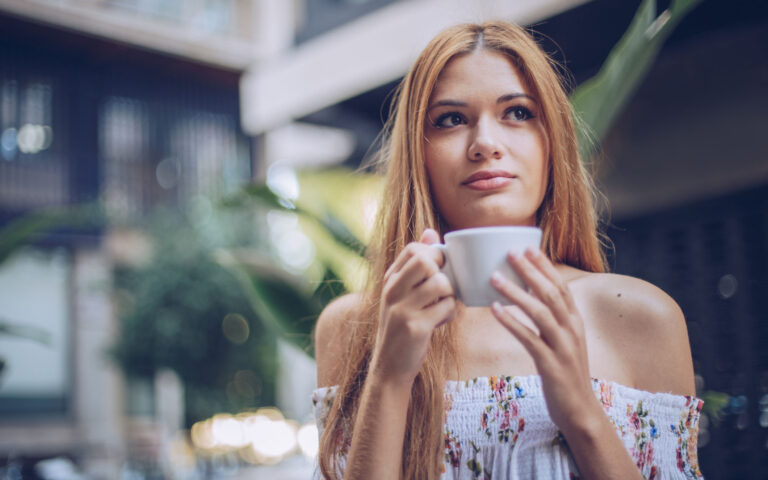 One blonde woman, holding a cup of coffee, on coffee break in cafe.