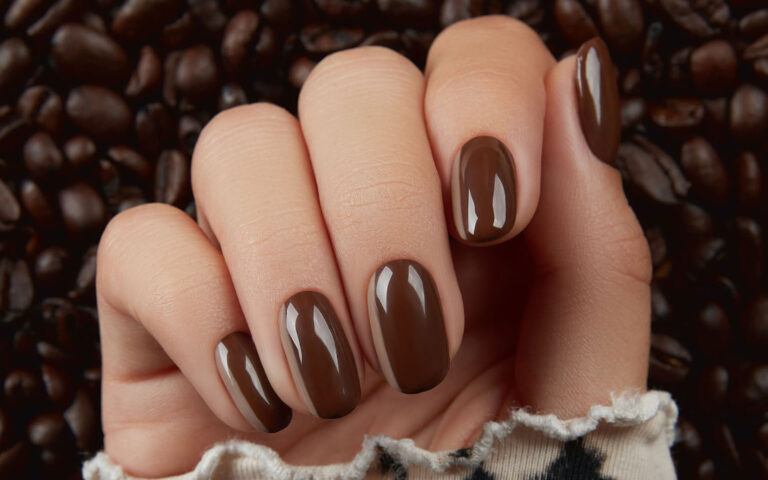Beautiful groomed womans hand with brown nail design. Manicure, pedicure beauty salon concept.