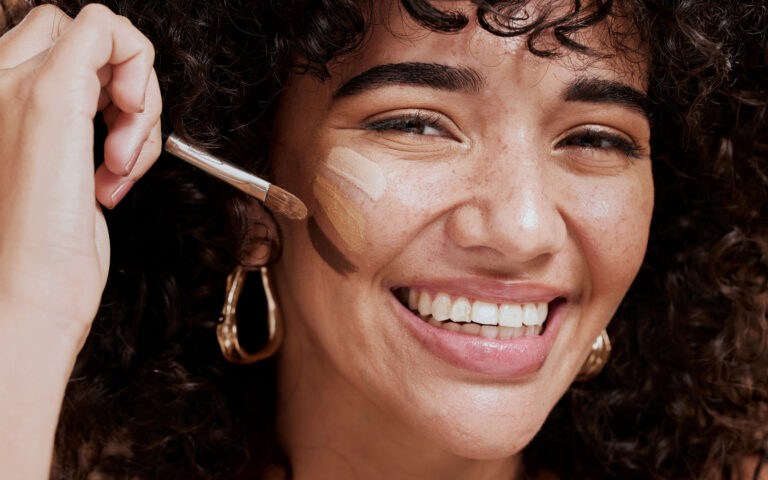 Face, makeup and brush with a woman black model applying foundation to her skin in studio for cosmetics. Portrait, wellness and luxury with an attractive young female using a cosmetic product Face, makeup and brush with a woman black model applying foundation to her skin in studio for cosmetics. Portrait, wellness and luxury with an attractive young female using a cosmetic product