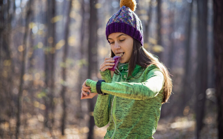 Woman eating nut bar while checking pace