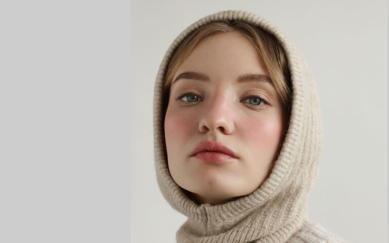 Portrait of young beautiful woman wearing beige knitted hood and sweater