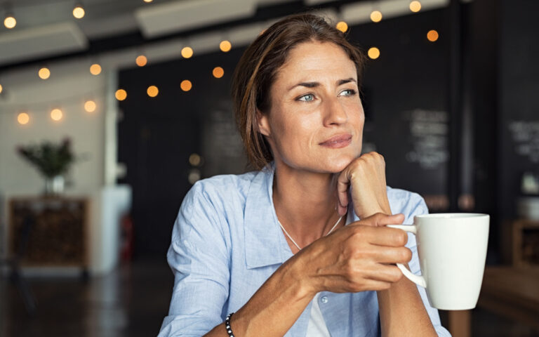 Thoughtful mature woman sitting in cafeteria holding coffee mug while looking away. Middle aged woman drinking tea while thinking. Relaxing and thinking while drinking coffee. Thoughtful mature woman sitting in cafeteria holding coffee mug while looking away. Middle aged woman drinking tea while thinking. Relaxing and thinking while drinking coffee.