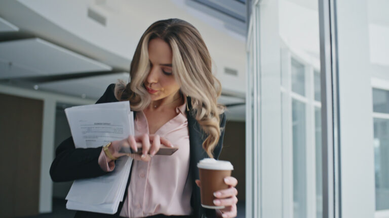 Busy woman going office hallway closeup. Late manager answering mobile phone holding coffee cup in morning. Corporate businesswoman multitasking walking with papers to meeting. Late employee calling. Busy woman going office hallway closeup. Late manager answering mobile phone holding coffee cup in morning. Corporate businesswoman multitasking walking with papers to meeting. Late employee calling.