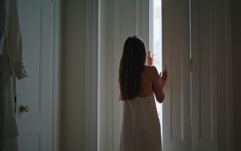 Tender lady opening shutters at bedroom. Relaxed woman looking window admiring views at home weekend. Unknown girl in silk nightgown enjoying lazy morning alone at dark place interior. New day concept Tender lady opening shutters at bedroom. Relaxed woman looking window admiring views at home weekend. Unknown girl in silk nightgown enjoying lazy morning alone at dark place interior. New day concept