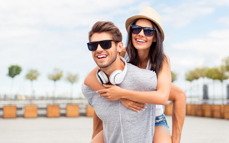 Handsome man carring his smiling girlfriend on back Handsome man carring his smiling girlfriend on back